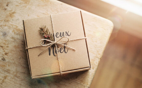 Rustic Christmas Gift Box on Wooden Table Tied with Twine and Pine Branch for Holiday Present