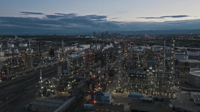 Oil refinery forward movement dusk hours blue industrial landscape and city skyline background aerial video Denver Colorado 4K