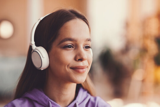 Smiling Young Woman With Headphones Enjoying Music At Home While Relaxing In Cozy Indoor Setting, Representing Feelings Of Joy And Calmness, Emphasizing Lifestyle And Wellness Concept.
