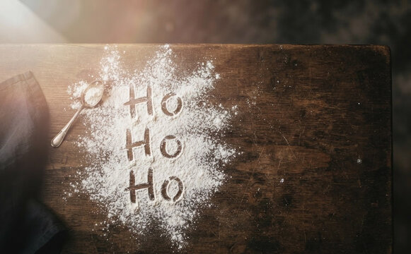 Rustic wooden table with flour spelling Ho Ho Ho for Christmas baking and holiday celebration concepts