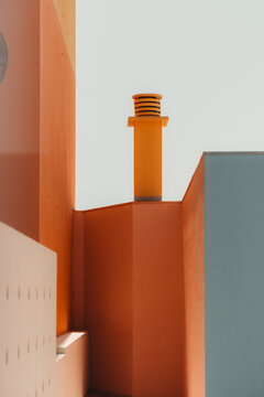 Minimalist view of vivid orange residential walls and a rooftop chimney against pale sky, with geometric lines, warm sunlight and generous negative space