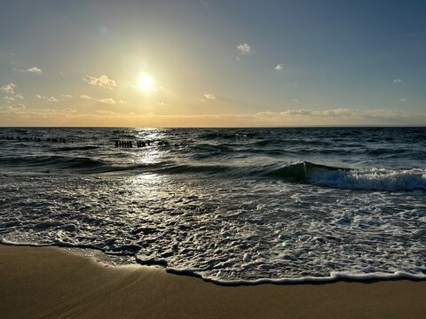 Setting sun over the Baltic sea with waves rolling towards the shore