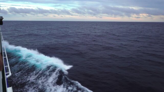 Passenger ship sailing through rough sea with heavy waves at dusk during a storm