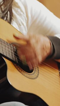 Musician strumming an acoustic classical guitar