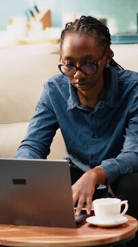 Vertical composition: Young woman cracking knuckles due to nervous habit at home, making repetitive involuntary popping sound as she is focused on tasks.