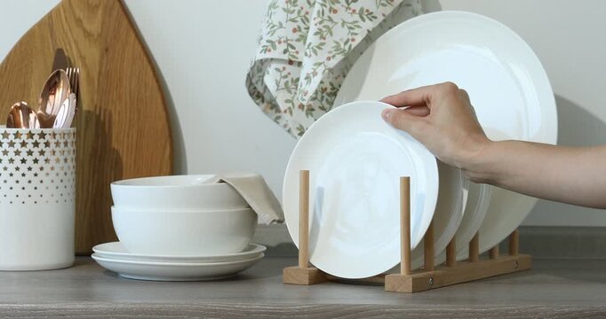 Woman with clean dishware, cutting board and cutlery at wooden table, closeup