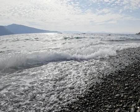 ​Clear sea waves crashing on pebble beach with foamy water during sunny day outdoors in summer time. As October approaches, summer continues in Fethiye.