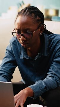 Vertical video: Distraught woman being troubled by work mistake and failure, struggling to avoid crisis or stressful situation. Worried anxious person working at home, puzzled and scared on the sofa.