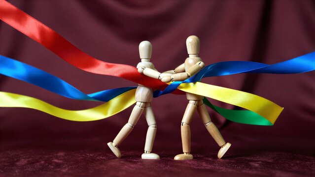 Two wooden figures dance with colorful ribbons against a rich red backdrop.