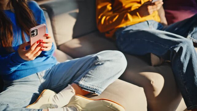 Coworkers scrolling phone sitting office lounge sofa. Close up hands texting.