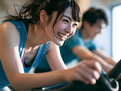 ジムのフィットネスマシンで懸命に運動する若い日本人女性