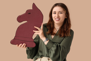 Strategic planning and business growth, young woman holding a large chess knight piece for leadership and decision making concept on beige background © Pixel-Shot