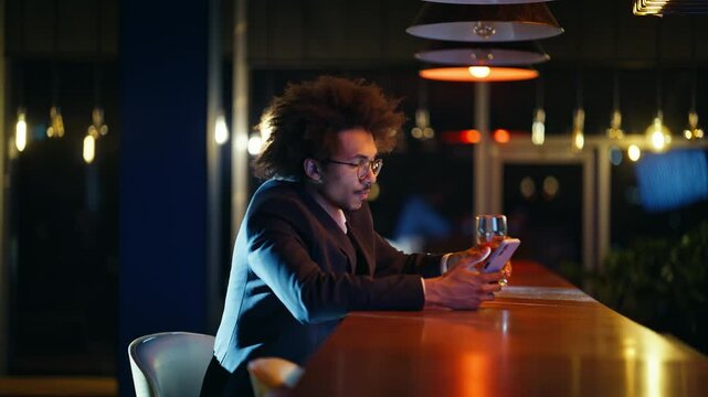 Businessman scrolling phone drinking beer bar counter. Evening nightlife alone.