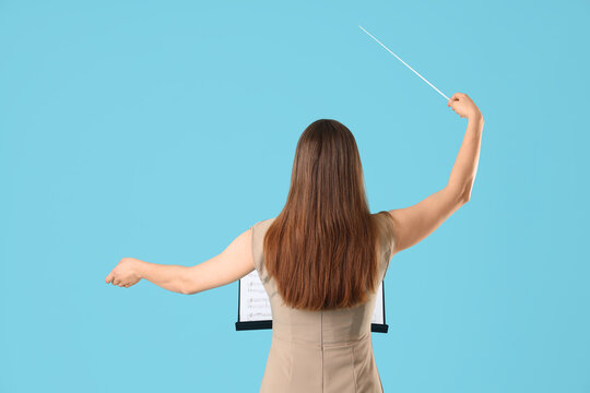 Young female conductor on blue background, back view