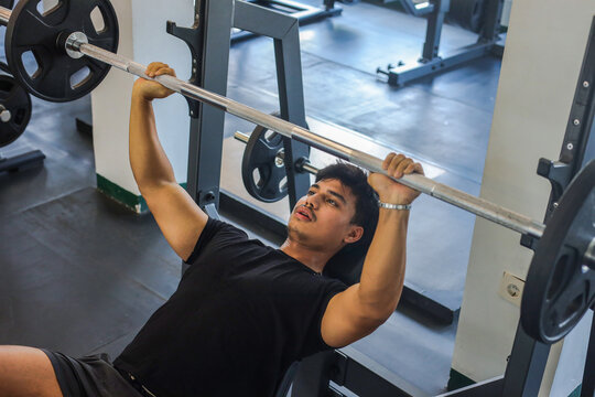 Focused Asian Male Athlete Lifting Heavy Barbell Weights