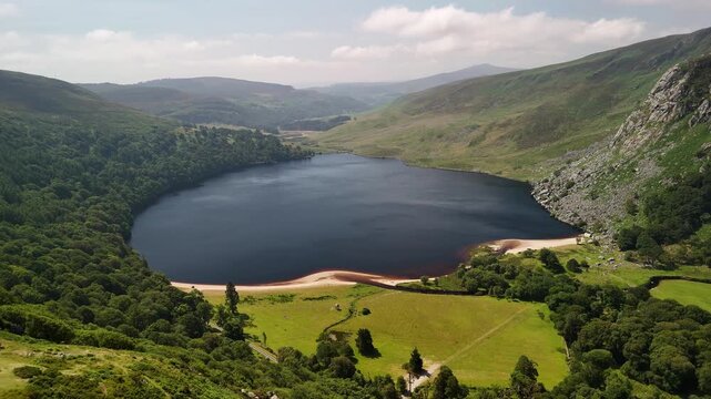 Aerial pullback from Lough Tay revealing a road and passing cars