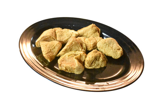 Fried stuffed tofu pieces served on black oval plate isolated on plain background