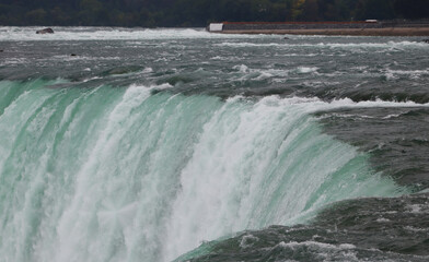 Wide horseshoe waterfall with wooded far shore and drifting spray © Marisa