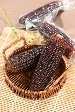 Black Purple Corn in Wicker Basket with Vacuum Packed Corn Background