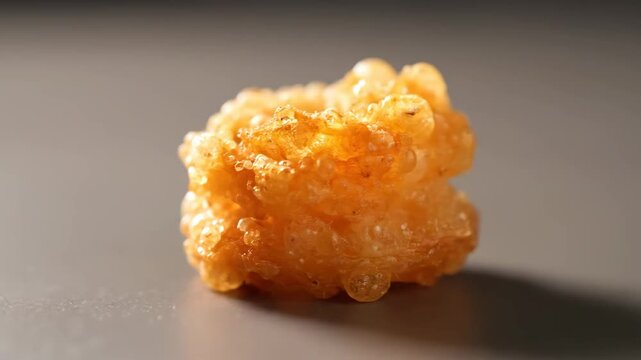 Extreme close-up macro shot of traditional Indian sweet Jalebi or Imarti, showing its detailed orange, syrupy, bubbly texture for food culture and dessert concepts.