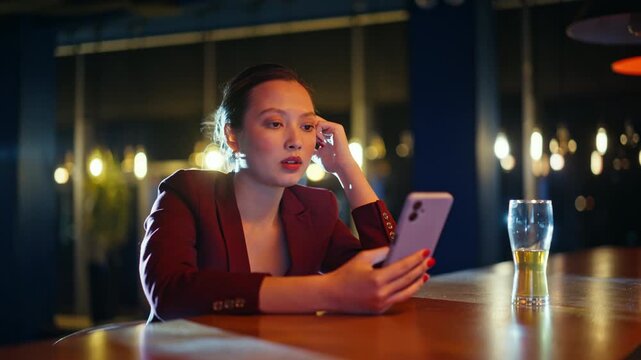 Businesswoman scrolling smartphone bar table. Woman waiting beer glass evening.