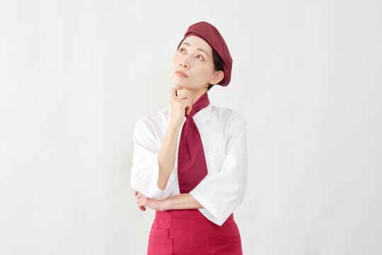 考えるポーズのパティシエ女性