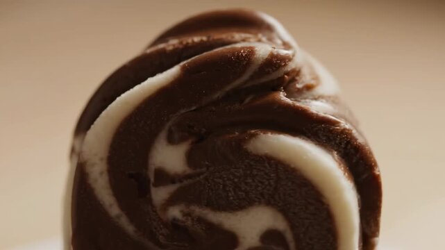 Extreme Close-up Macro Shot of Marbled Chocolate and Vanilla Swirl Ice Cream Dessert Texture Against a Beige Background.