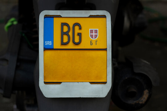Photo of yellow bike license plate with Belgrade BG code, SRB monogram, letter B and G, national coat of arms on rear fender. Concept of travel, vehicle registration identifier, transport, identity