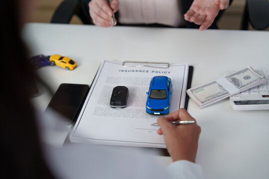 Client signing car insurance policy document at desk for auto loan
