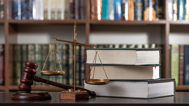 A judge's gavel and the scales of justice against a background of books and a bookshelf.
