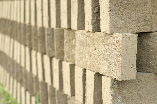 Close-up of unfired clay bricks mixed with straw chaff stacked neatly in rows to dry