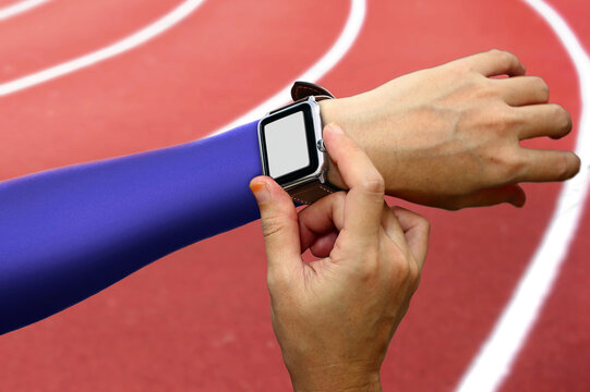 Fitness smartwatch mockup on athlete's wrist with blank screen overlay  on running track at sports stadium.