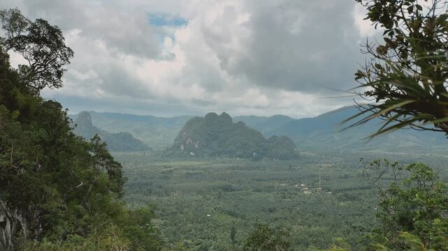 Expansive view of verdant mountains and tropical forests under a dramatic cloudy sky.