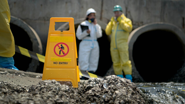 Warning sign and hazardous work area near polluted wastewater drainage tunnel
