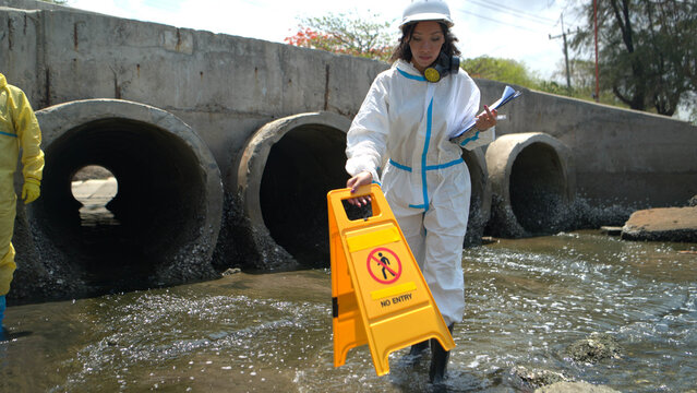Warning sign and hazardous work area near polluted wastewater drainage tunnel