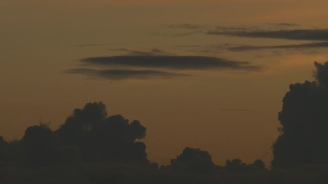 Silhouetted Clouds Against Bold Orange Sunset Gradient Sky