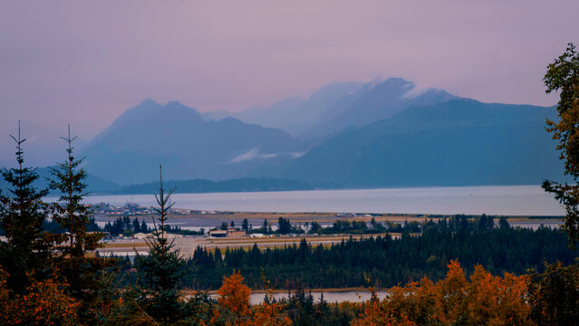 Alaska autumn sunset seascape at Homer Spit harbor and Kachemak Bay with view of foggy Kenai Mountains