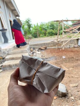 Hand Holding a Traditional Indonesian Wrapped Rice Food Parcel Outdoors