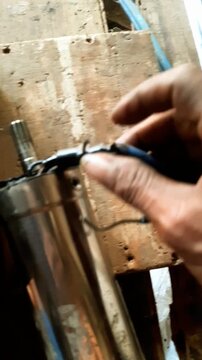 
Close up of technician hand repairing submersible deep well water pump. Man fixing and connecting electric cable wire of stainless steel submersible pump on wooden workbench, water pump main