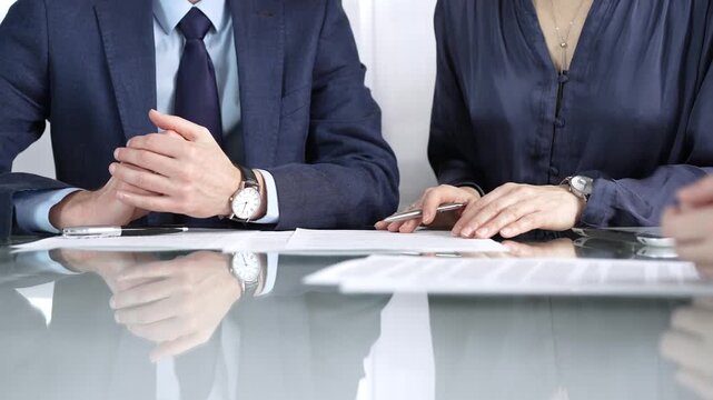 Business partners or lawyers are discussing contract papers during a meeting, negotiating and making decisions together. Business people concept, close up