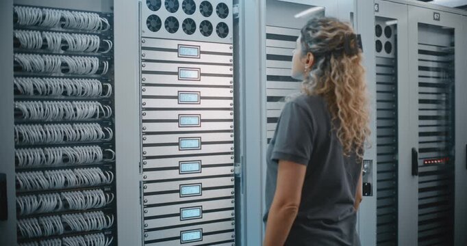 Female Technician Operates LED Controls on Server Cabinet Inside Large Data Center, Performing Hands on Equipment Management. Concept of Hardware Control, Technical Service and Maintenance of Servers.