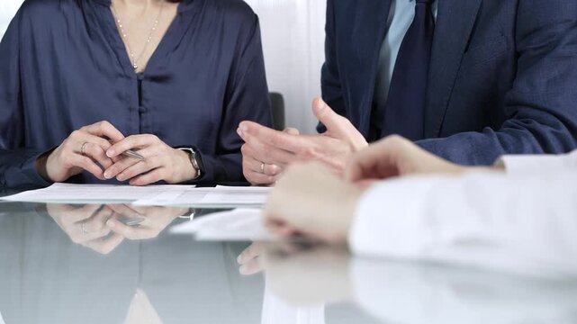 Business partners or lawyers are reviewing contract terms during a meeting, negotiating and making decisions together. Business people concept, close up view