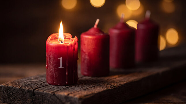 A single red advent candle with the number one burns brightly on a rustic wooden board, with three unlit candles in the soft-focus bokeh background.