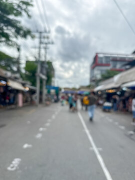 blurred view of people and a busy crowd walking down a street in an outdoor market