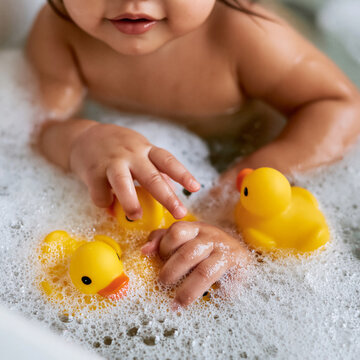Small hands exploring bubbles and yellow ducks during a joyful bath time experience Generative AI