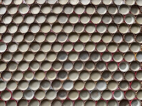 Vintage metal beer bottle caps texture background pattern. Repeating rows of crown caps backdrop for craft beverage design. Minimalist metallic bottle cap grid surface with copy space.