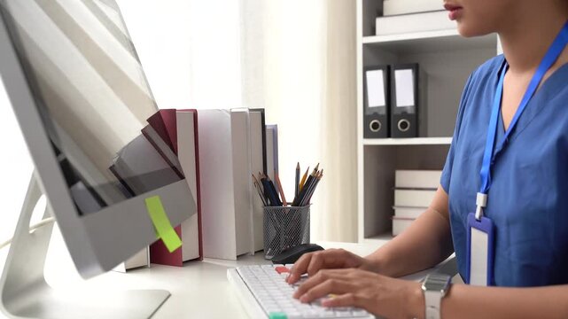 Doctor Typing on Computer: A medical professional intently works on a computer keyboard in an office setting, surrounded by medical books and patient records.