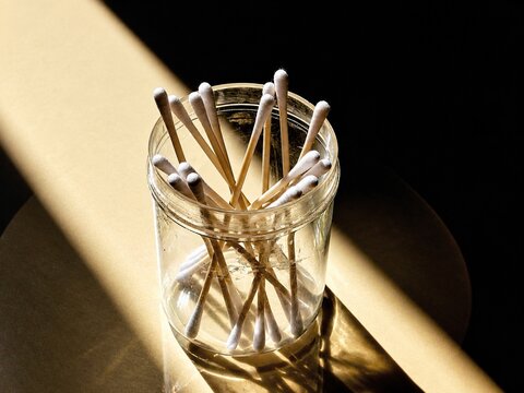 Glass jar holds cotton swabs in warm sunlight
