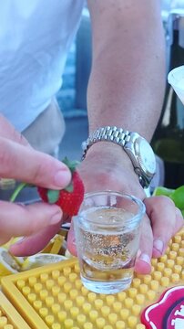 A bartender serves refreshing colorful drink at an outdoor beach bar. Bartender prepares and serves cocktails. Summer concept.