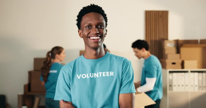 Happy man, volunteer and face in NGO with arms crossed, community service and outreach program. Coordinator, confident and laugh at centre for food drive, social responsibility or project about us